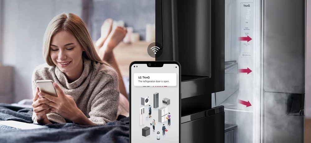 Chladnička s mrazničkou LG GBBS312APY nerez žena s úsmevom na tvári zisťuje na mobilnom telefóne cez aplikáciu LG thinQ, že má otvorené dvierka od chladničky.