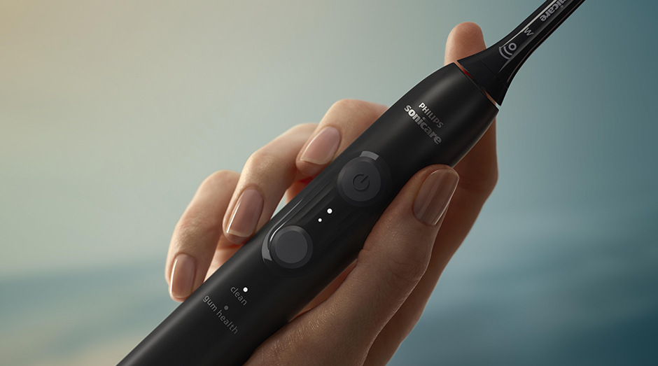 Zubná kefka Sonicare drží žena v ruke a idú vidieť tlačidlá na kefke