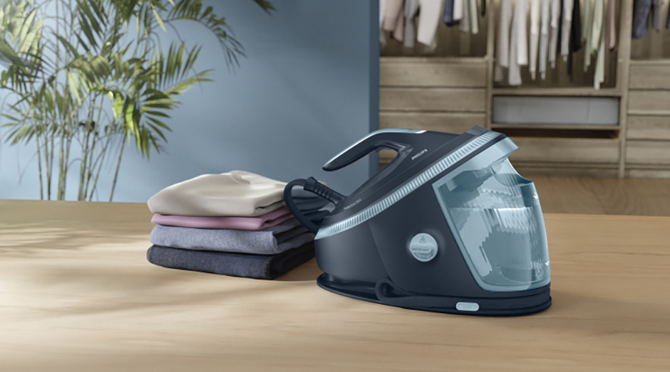 Žehliaci systém Philips 7200 Series PSG7200/20 tmavo modrá farba Žehliaci systém Philips PSG7200/20 7200 Series vedľa poskladanej a vyžehlenej bielizne