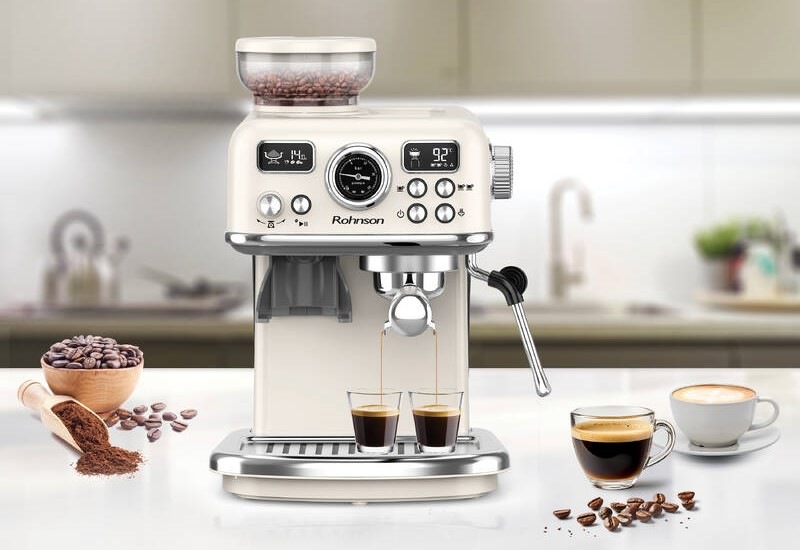 Pákový kávovar Rohnson R-98250C 2v1 krémový Elegantný pákový kávovar Rohnson R-98250C 2v1, ktorý práve pripravuje súčasne dve kávy, vedľa neho je postavená šálka s cappuccinom a ako dekorácia je obrázok doplnený kávovými zrnami aj namletou kávou.