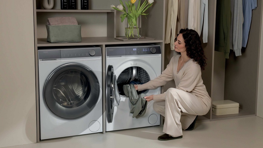 Sušička bielizne Haier HD80-C367TU1-S biela žena vkladá bielizeň do slim sušičky haier HD80-C367TU1-S, ktorá sa nachádza v práčovni vedľa práčky
