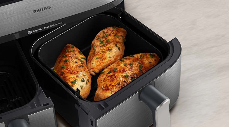 Fritéza teplovzdušná Philips Airfryer Dual Basket 5000 series 9 l, NA555/00 strieborná Teplovzdušná fritéza Philips má povysunutý kôš, v ktorom sa práve ohrialo mäso.