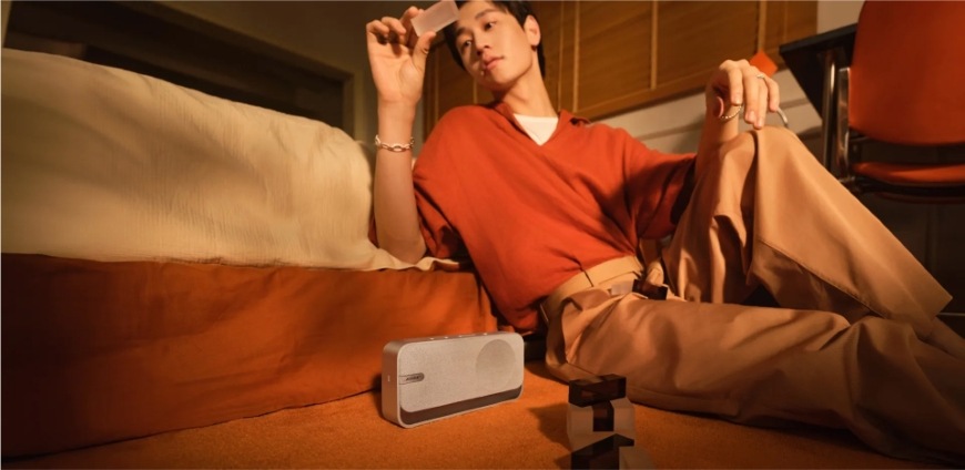 Prenosný reproduktor Bose Soundlink HOME strieborný Muž sediaci na sedačke s kompaktným reproduktorom Bose SoundLink Home