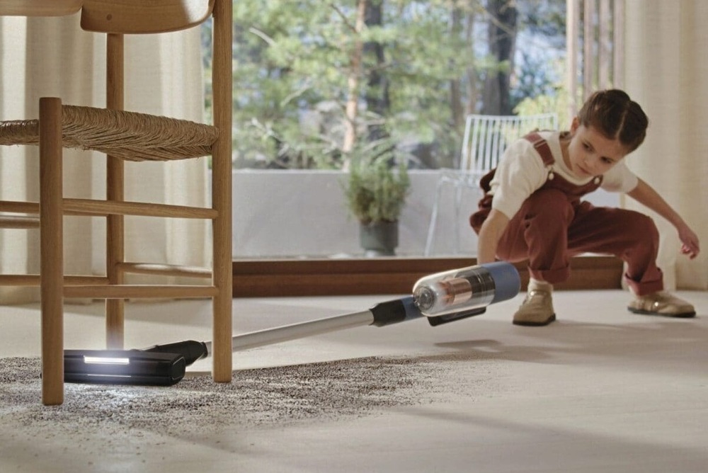 Tyčový vysávač Electrolux 700 Hygienic EP72H21WET modrý Dievčatko vysáva neporiadok pod stoličku s pomocou vysávača Electrolux.