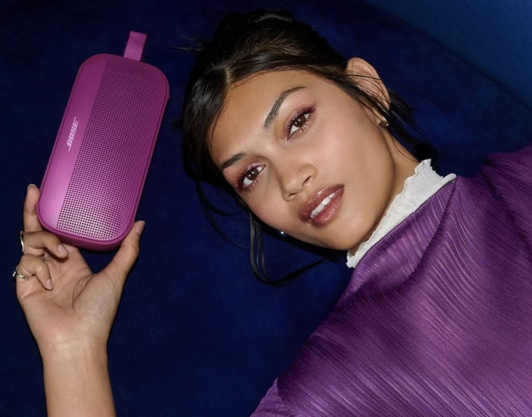 Žena držiaca v ruke fialový prenosný reproduktor Bose SoundLink Flex II