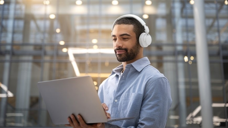 Muž s notebookom v ruke má hlave slúchadlá Philips TAH4500