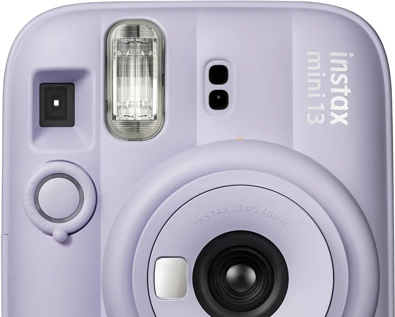 Instantný fotoaparát Fujifilm instax mini 13 fialový Detail prednej strany fotoaparátu Fujifilm instax mini 13 s indikátorom samospúšte vedľa objektívu