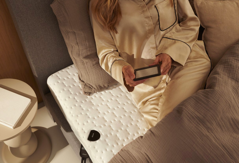 Vyhrievacia podložka Duux Duux DXUB12 Snooze Fleece 200 x 155 cm biela Žena relaxujúca na vyhrievacej podložke Duux DXUB12 Snooze pri večernom čítaní v posteli