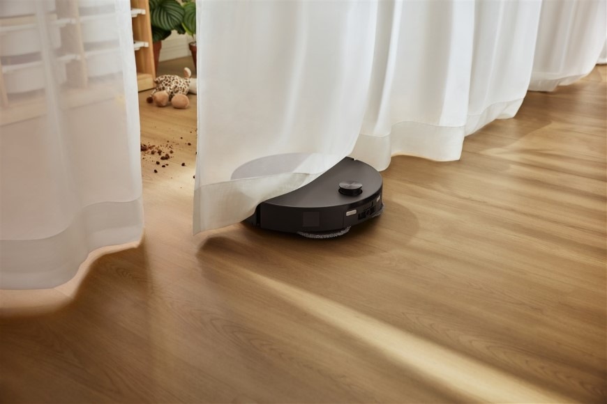Robotický vysávač Roborock Qrevo Edge 2 Black čierny Vysávač Qrevo Edge 2 prechádza pod záclonami do ďalšej časti miestnosti s vysypaným neporiadkom