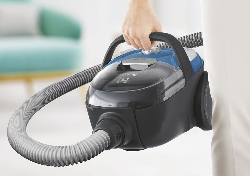 Žena drží za madlo vysávač Electrolux ECGC21-2CB CompactGo Cyclonic