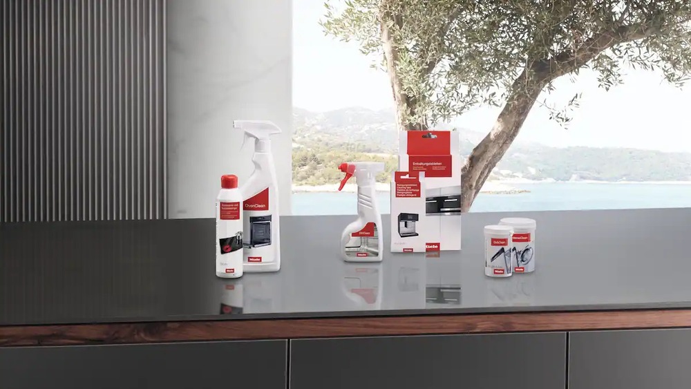 Čistiaci prípravok Miele 500 ml OvenClean GP CL H 0502 L položený na kuchynskej linke s ďalšími čistiacimi prípravkami
