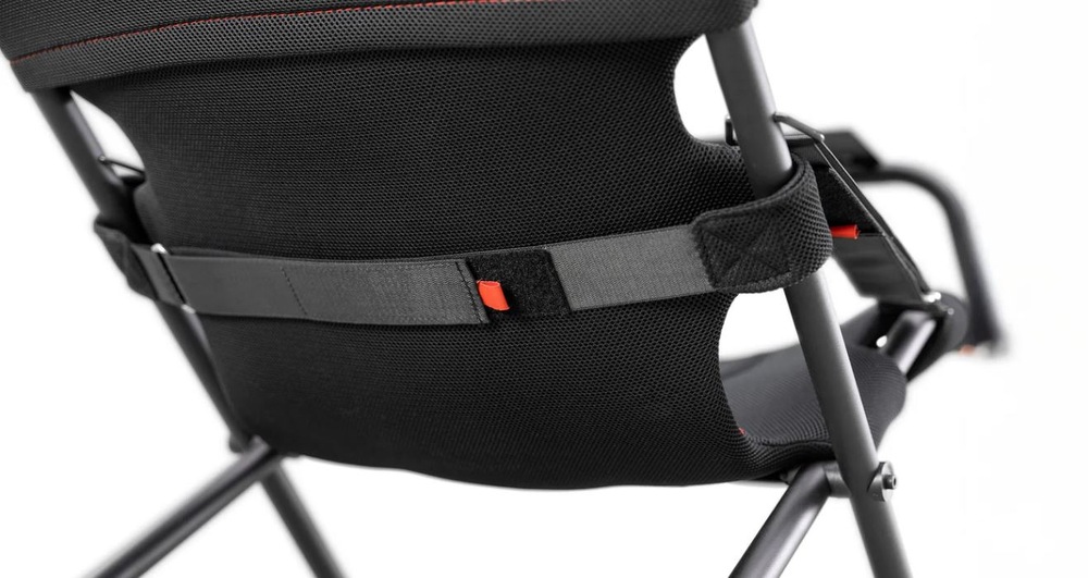 Detailný záber na čierne sieťované operadlo stoličky s nastaviteľným bedrovým oporným pásom a oranžovými detailmi. Dizajn je moderný, s dôrazom na pohodlie a ergonómiu.