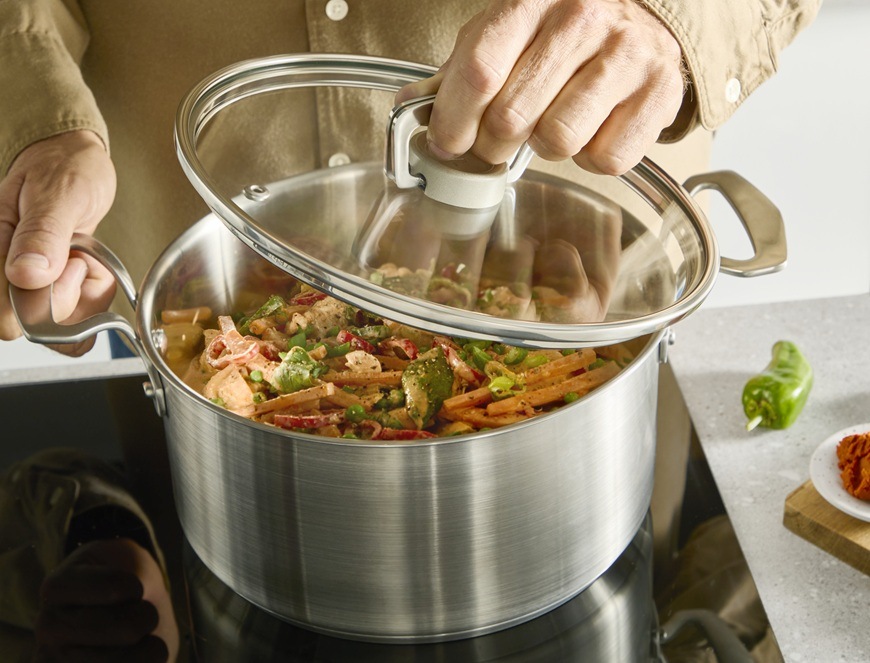 Hrniec s pokrievkou Tefal Extreme E5296104, 22 cm nerez Muž drží nad hrncom Tefal pokrievku a mieša zeleninu.