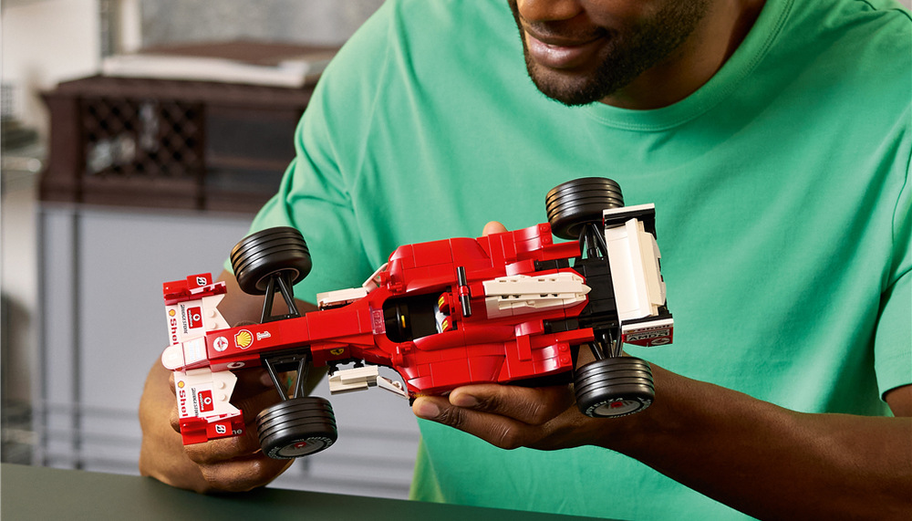 Stavebnica LEGO® Icons 11375 Ferrari F2004 a Michael Schumacher Minifigúrka Michaela Schumachera s helmou a trofejí dopĺňa podstavce s informáciami o legendárnom Ferrari F2004.