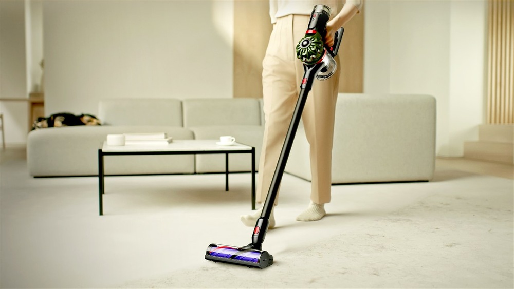 Žena vysáva s tyčovým vysávačom Dyson V8