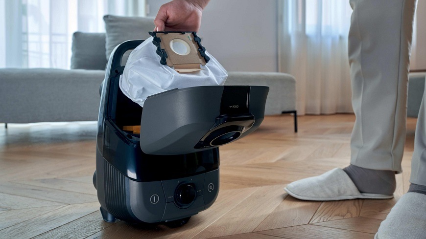 osoba vyberá vrecko z vysávača hoover HE210P 011″ width=