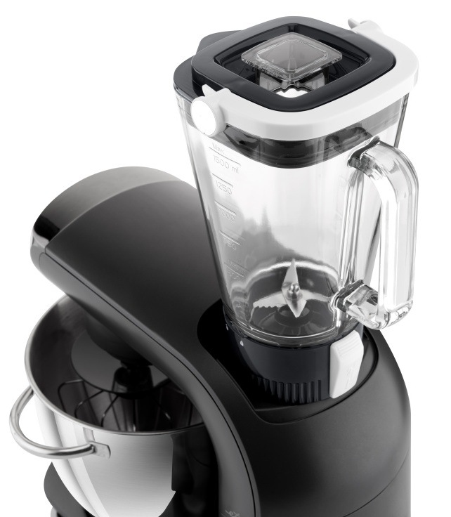 Sklenený mixovací nadstavec kuchynského robota ETA Gratus Evo Origin II naplnený čerstvým ovocím (jahody, kivi, banán, mango). Pohľad zhora demonštruje horný vývod na mixovanie smoothies a koktailov, zatiaľ čo v nerezovej mise je nasadená šľahacia metla na súbežnú prípravu