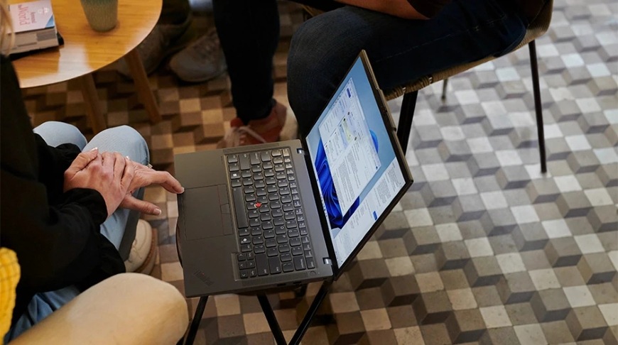 Pohľad zhora na človeka pracujúceho na laptope Lenovo ThinkPad T14 Gen 6″ width=