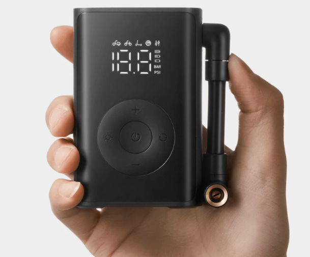 Kompresor Xiaomi Mijia Compact Portable držaný v ruke so zapnutým displejom a ovládaním