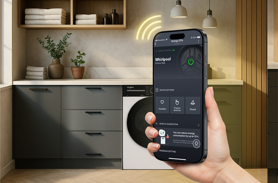 RRuka držiaca chytrý telefón s aplikáciou HomeWhiz v pozadí práčka Whirlpool v práčovni s poskladanou bielizňou na skrinke