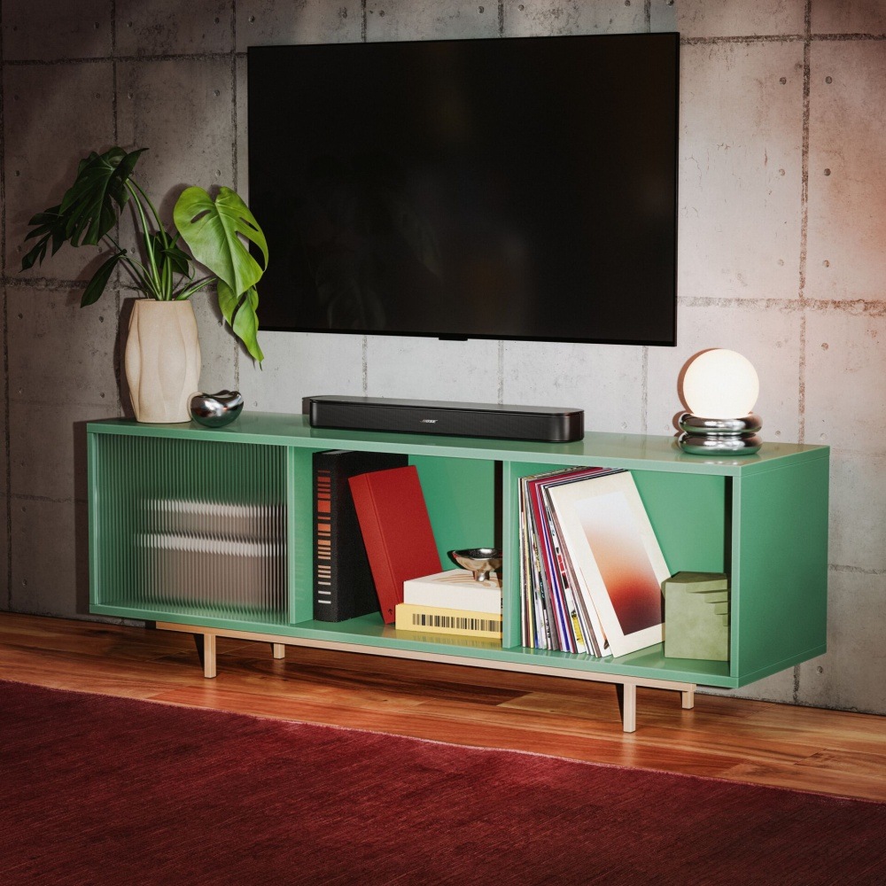 Soundbar Bose TV Speaker 2nd.Gen. čierny Soundbar Bose TV Speaker pod televíziou na zelenom televíznom stolíku v obývacej izbe.