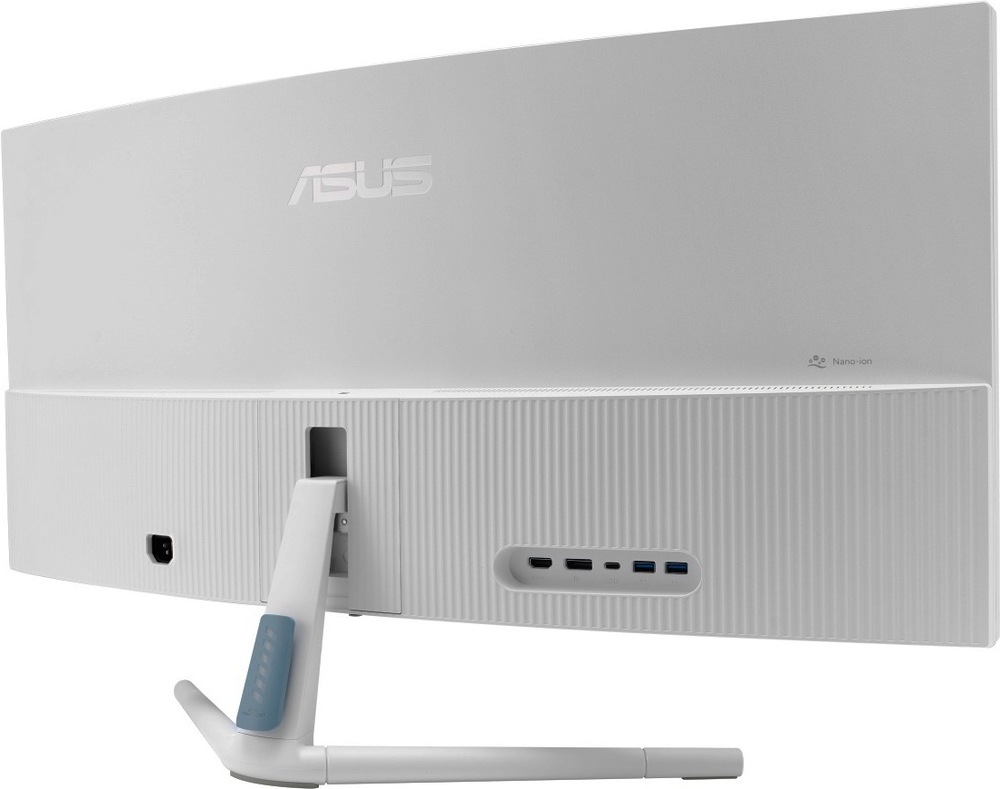 Monitor Asus VU34WCIP-W biely Na obrázku je zadná strana monitora Asus VU34WCIP-W 34" v bielom prevedení zo šikmého pohľadu. Je vidieť široké prehnuté telo displeja, svetlý zadný kryt s jemným zvislým rebrovaním a decentné logo Asus. Uprostred je uchytenie bieleho stojana so svetlo modrým detailom. Na zadnej strane sú vidieť porty, vľavo na vidieku časti je označenie Nano-Ion.