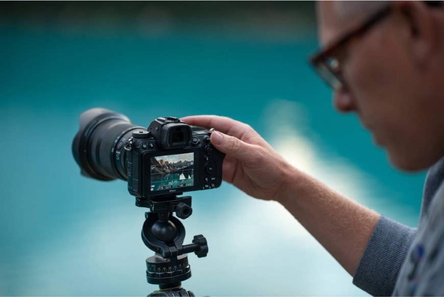 Muž nastavuje fotoaparát na statíve vybavený objektívom NIKKOR Z 24–120 mm f/4 S