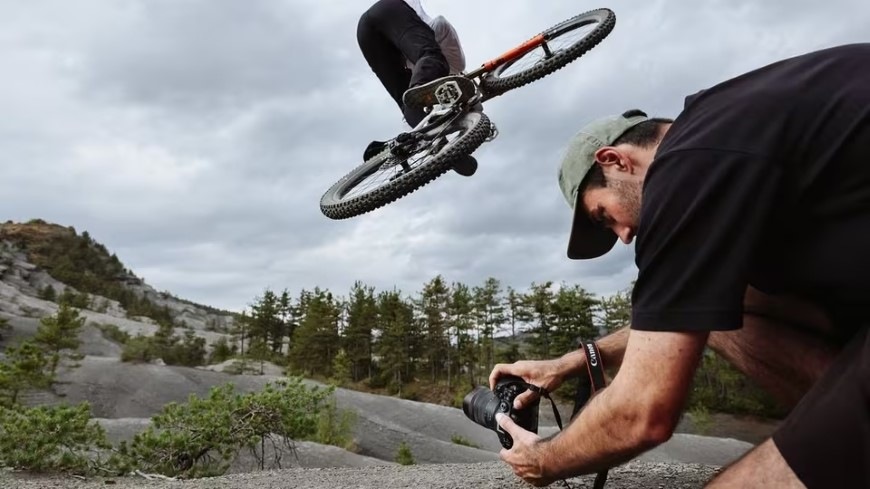 Digitálny fotoaparát Canon EOS R6 Mark III + RF 24-105 mm f/4-7.1 IS STM čierny Muž fotografujúci skoky na bicykli s bezzrkadlovkou Canon EOS R6 Mark III vybavenou funkciou predsnímania