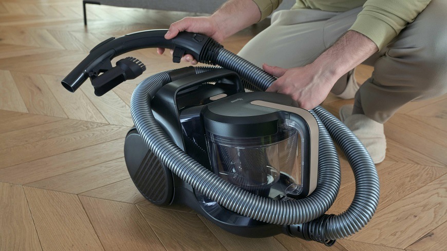 Podlahový vysávač Hoover HP410P 011 čierny/béžový HP410P 011 osoba omotáva hadicu okolo vysávača