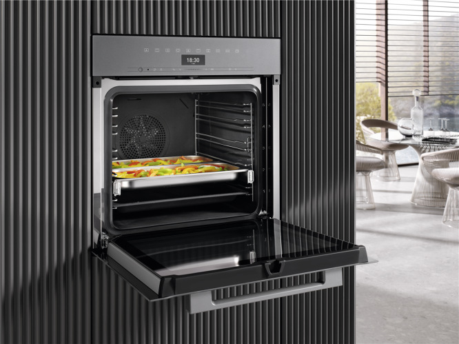Rúra Miele DGC 7450 Nerezová ocel/čistá ocel nerez Otvorená parná rúra Miele DGC 7450 vstavaná v kuchyni s pečenou zeleninou na plechu.