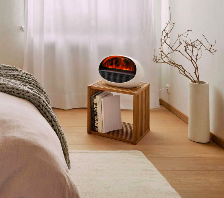 Teplovzdušný ventilátor Stadler Form Erik na stolíku vedľa postele s efektom plameňa