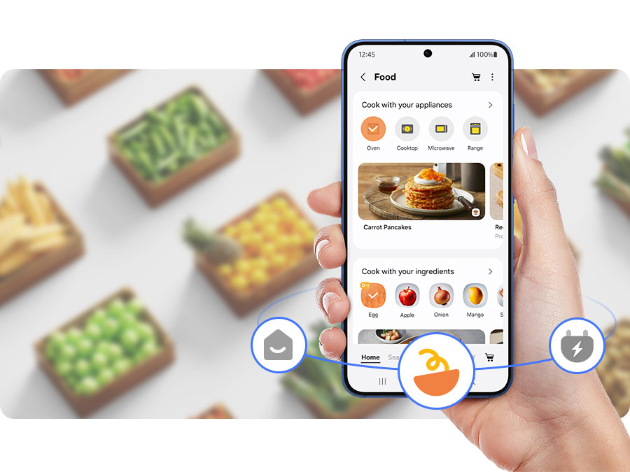 Americká chladnička Samsung RM70F63NEREO nerez/ocel Ruka drží mobilný telefón s otvorenou aplikáciou SmartThings Food, na pozadí sú krabice s jedlom