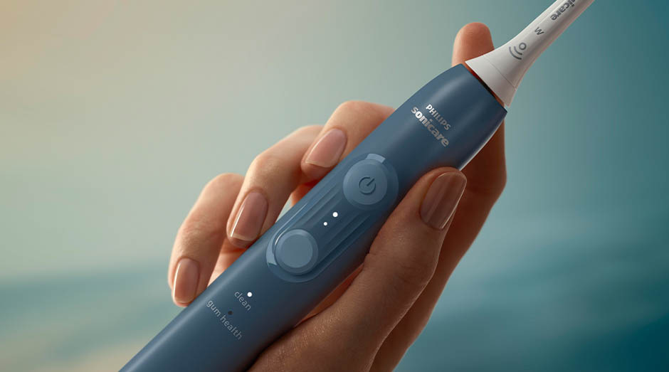 Zubná kefka Sonicare drží žena v ruke a idú vidieť tlačidlá na kefke