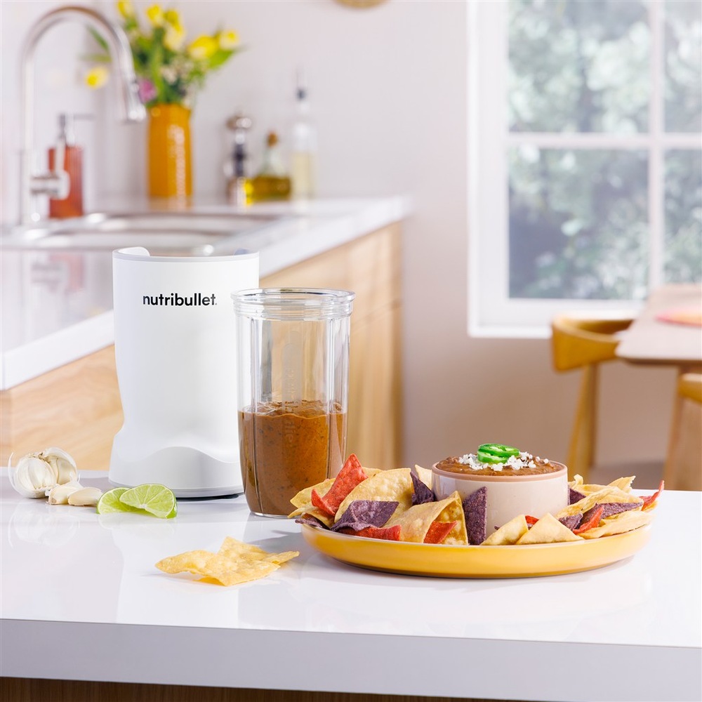 Stolný mixér Nutribullet TURBO 1000 NBT1006MW biely Mixér NutriBullet použitý na prípravu omáčky, vedľa taniera s tortilla chips a dipom.