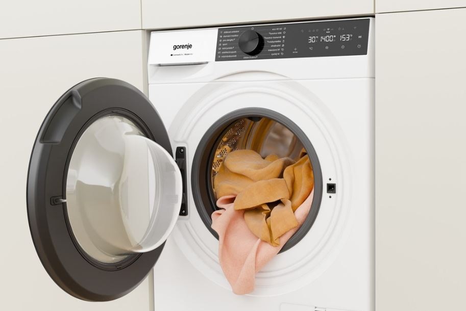 práčka gorenje s otvorenými dvierkami, sú vidieť uteráky, ktoré čiastočne visí z bubna von.