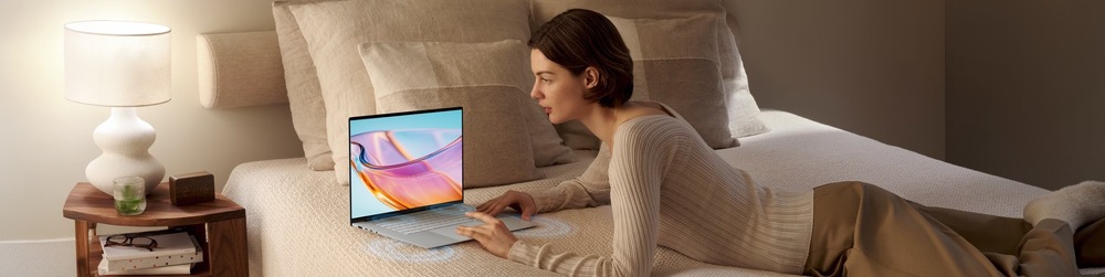 Žena sleduje film na displeji notebooku Asus Zenbook S16 z pohodlia postele