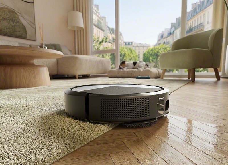 Robotický vysávač iRobot Roomba Plus 415 Combo nabieha z drevenej podlahy na koberec a súčasne dvíha mopovacie podložky, takže koberec zostane suchý.