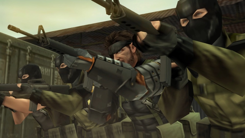 Scéna z hry Metal Gear Solid: Peace Walker. Traja ozbrojení vojaci v taktickom vybavení a maskách mieriacimi puškami, zasadení do napätého, prašného prostredia. Postava uprostred je bez masky a má sústredený výraz.