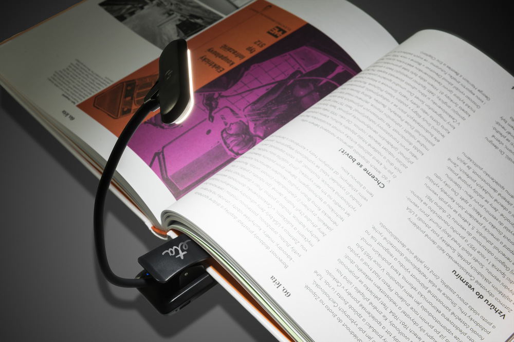 Stolná lampa ETA 089490000 s klipom, nabíjacia, stmievateľná čierna Čierna LED lampička ETA 0894 s klipom pripnutá na rozčítanej knihe, osvetľujúca text teplým svetlom.