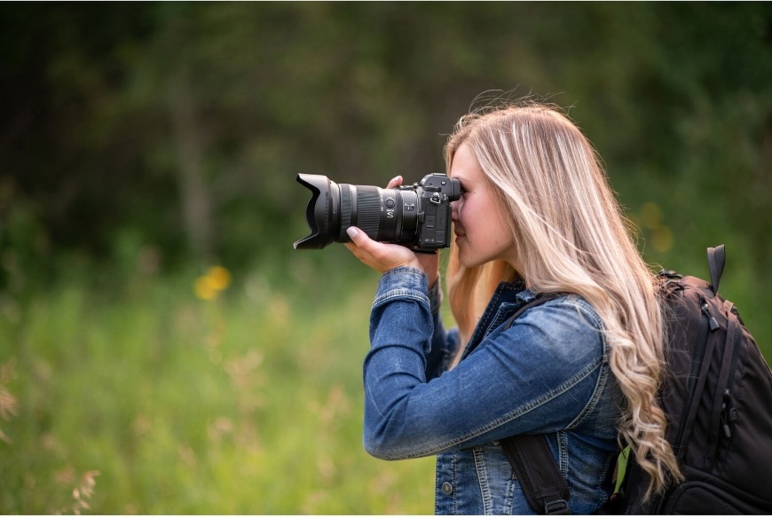 Žena v prírode fotografuje pomocou všestranného objektívu NIKKOR Z 24–120 mm f/4 S
