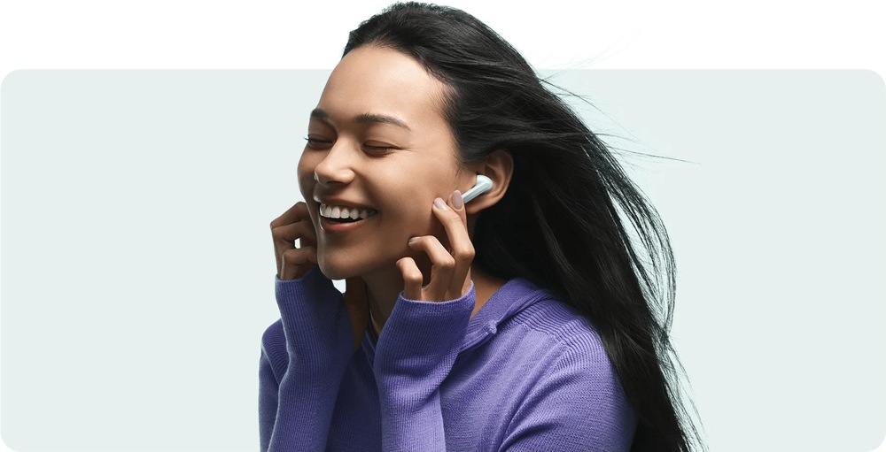 Slúchadlá Xiaomi Buds 6 Ceramic White biela Smejúca sa žena s vlajúcimi vlasmi od vetra so slúchadlami Xiaomi Buds 6 vybavenými redukciou šumu pri fúkaní vetra
