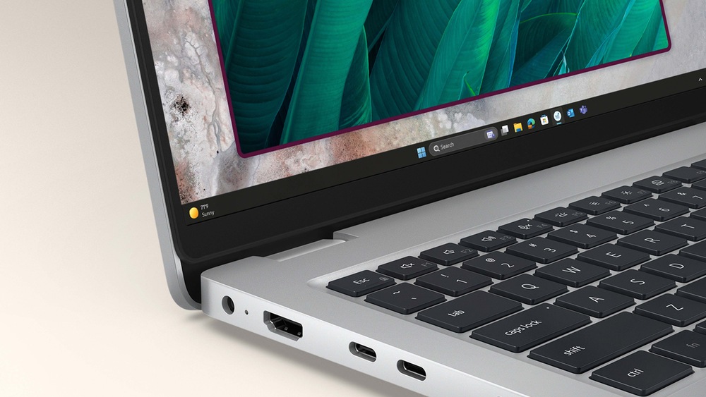 Detailný záber na čiastočne otvorený elegantný notebook zobrazujúci živú zelenú tapetu s motívom listov. Dôraz je kladený na klávesnicu, porty HDMI a USB-C, ktoré symbolizujú modernú technológiu.