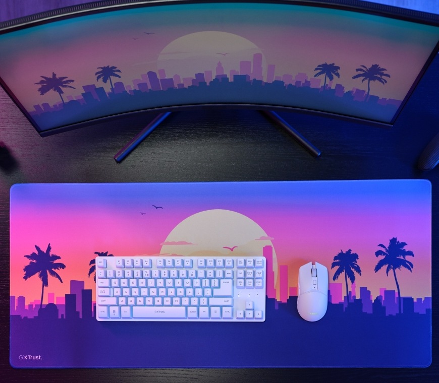 Klávesnica s myšou Trust GXT 882 Wireless - TKL Keyboard, Mouse & XXL Mousepad Miami - CZ/SK biela farba Klávesnica a myš Trust GXT 882 Miami na podložke pred monitorom s motívom západu slnka