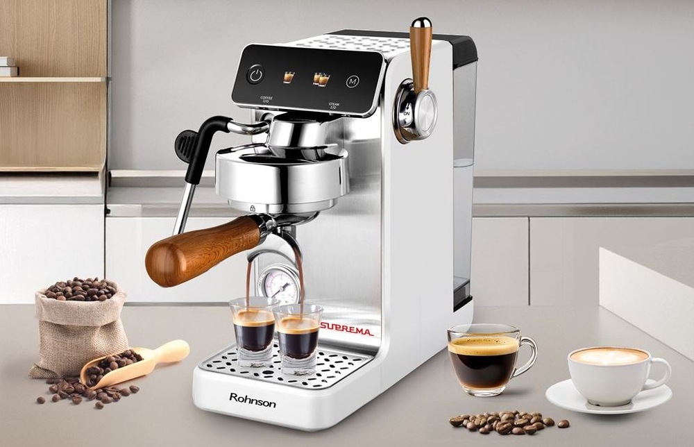 Pákový kávovar Rohnson R-98300 Suprema strieborná farba Kávovar Rohnson R-98300 Suprema stojí na kuchynskej linke. Pripravuje zároveň dve šálky, vedľa neho je vrecko s kávou, na druhej strane stojí espresso a cappuccino.