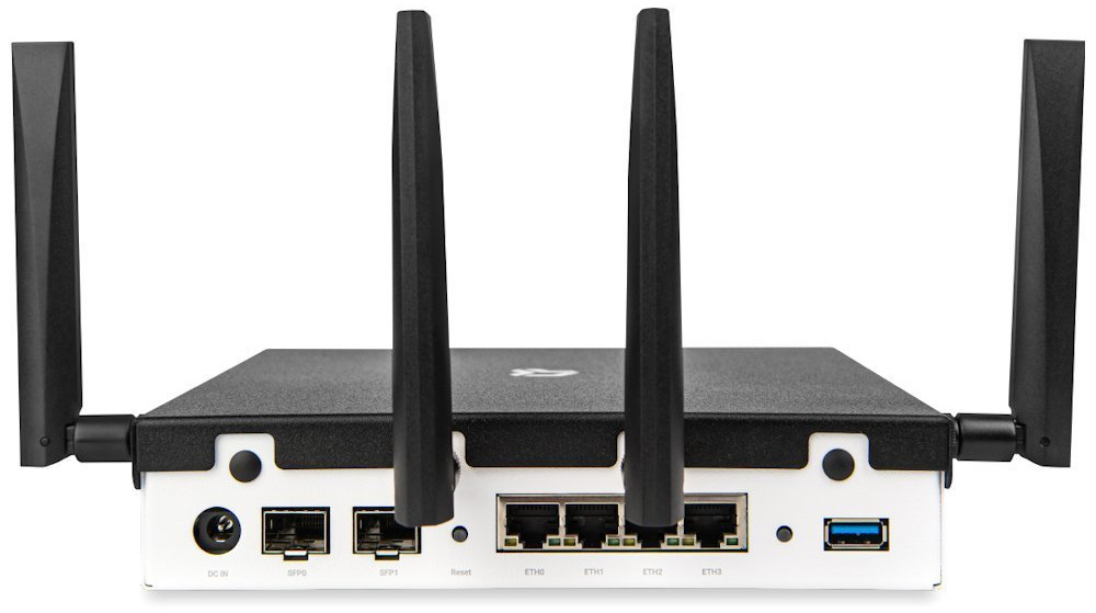 Router CZ.NIC Turris Omnia NG Wi-Fi 7 čierny Na obrázku je zadná strana routera Turris Omnia NG Wi-Fi 7. Z hornej časti vystupujú štyri antény, dve krajné po stranách a dve uprostred, ktoré čiastočne zakrývajú konektory. Na spodnej bielej časti sú vidieť napájací vstup, dva SFP porty, tlačidlo Reset, štyri sieťové porty Ethernet a vpravo modrý USB port.