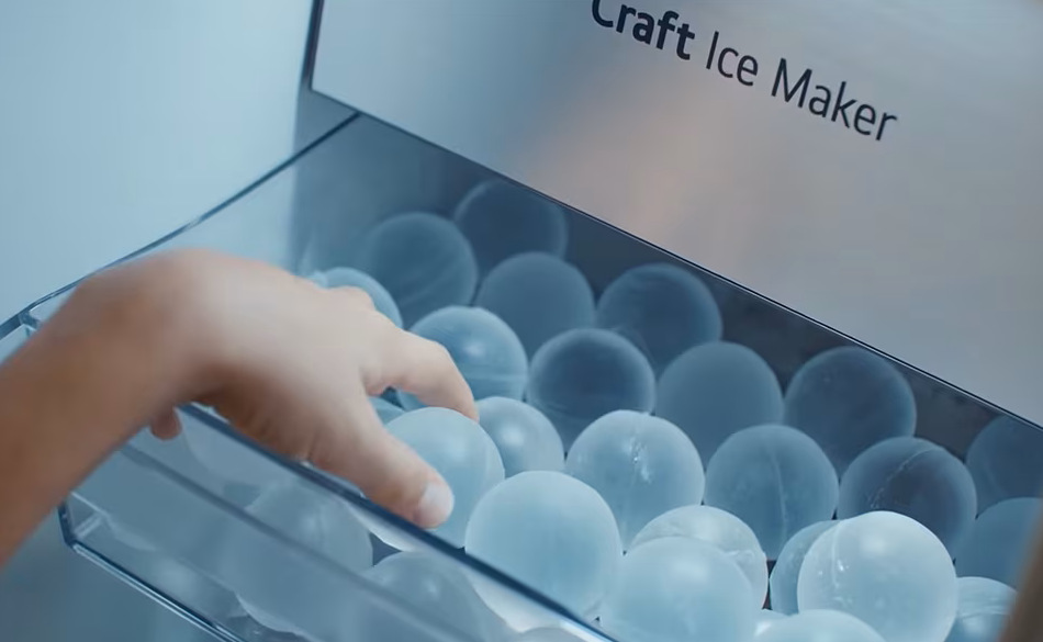 Dieťa sa naťahuje po ľad v tvare gule z výrobníka ľadu.