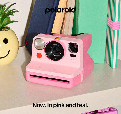 Instantný fotoaparát Polaroid Now Gen 3 ružový Ružový instantný fotoaparát Polaroid Now Gen 3 položený na stole vedľa kníh a dekorácií v modernom interiéri