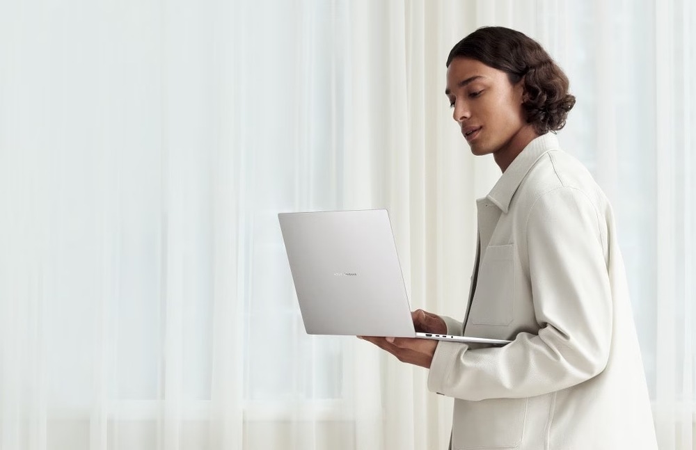 Notebook Asus Zenbook S16 OLED biely Žena drží v jednej ruke ľahký a elegantný Zenbook S16