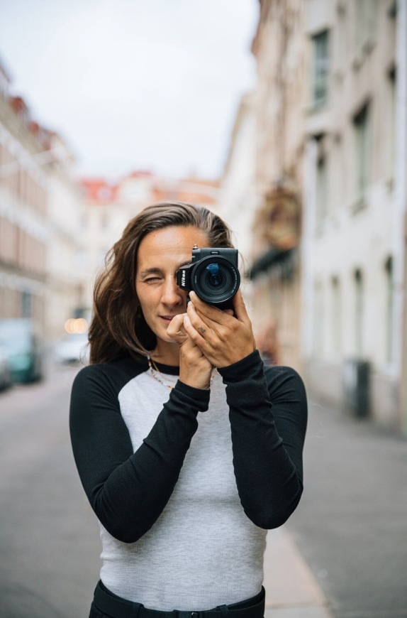 Objektív Nikon Z DX 16-50 mm f/2.8 VR čierny Pohľad spredu na fotografujúcu ženu s kompaktným sklom NIKKOR Z DX 16–50 mm f/2.8 VR