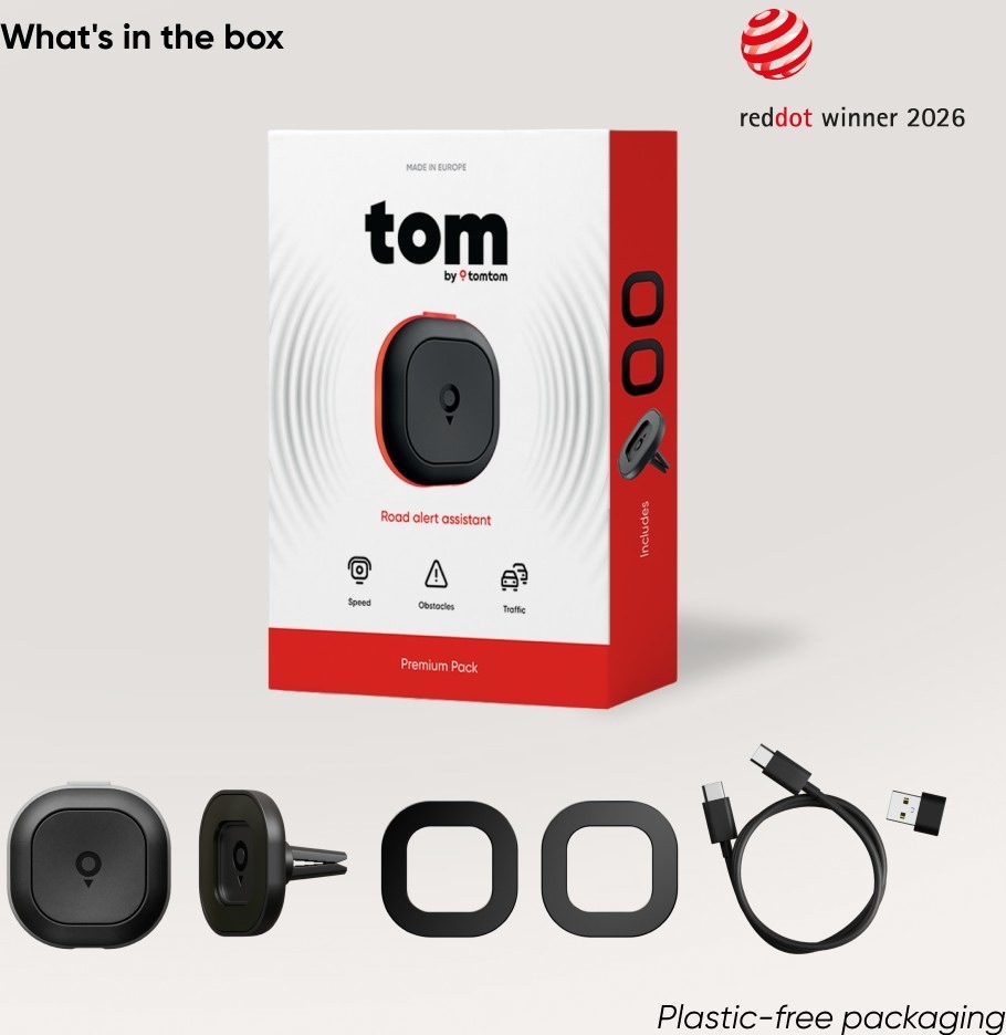 Balenie TomTom Tom Premium Pack s cestovným asistentom, držiakom do ventilačnej mriežky, dvoma adhezívnymi držiakmi, nabíjacím káblom USB-C a redukciou USB-A. Vpravo hore je označenie Red Dot Winner 2026.